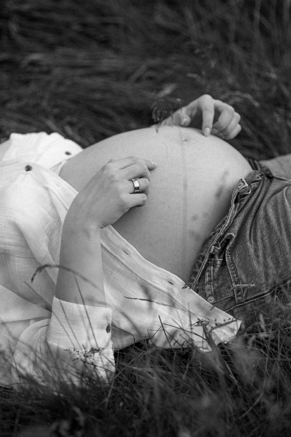 A black and white artistic maternity photo showing a pregnant belly in nature.