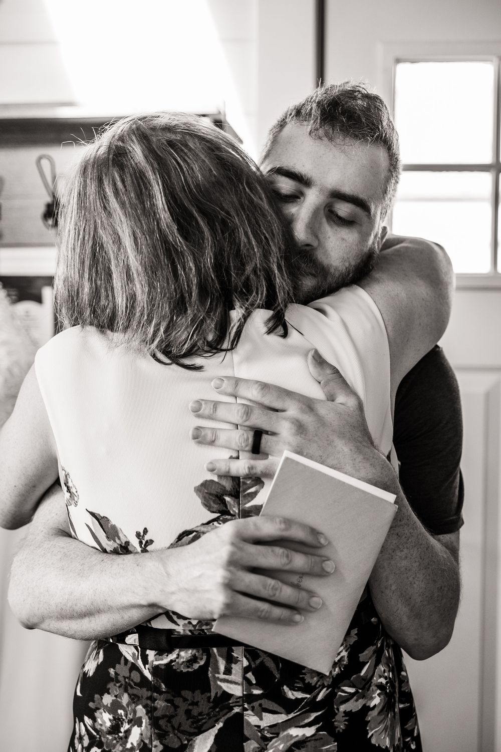 A sequence of black and white photographs showing people embracing and hugging in tender moments.
