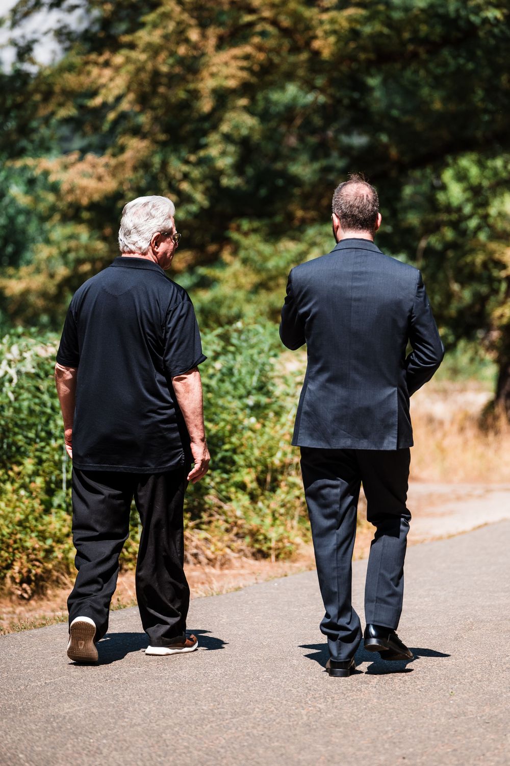 A series of silhouettes showing two people kneeling on a path surrounded by greenery.