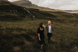 Two people walking and laughing together on a beautiful hillside trail in the Scottish Highlands during golden hour.
