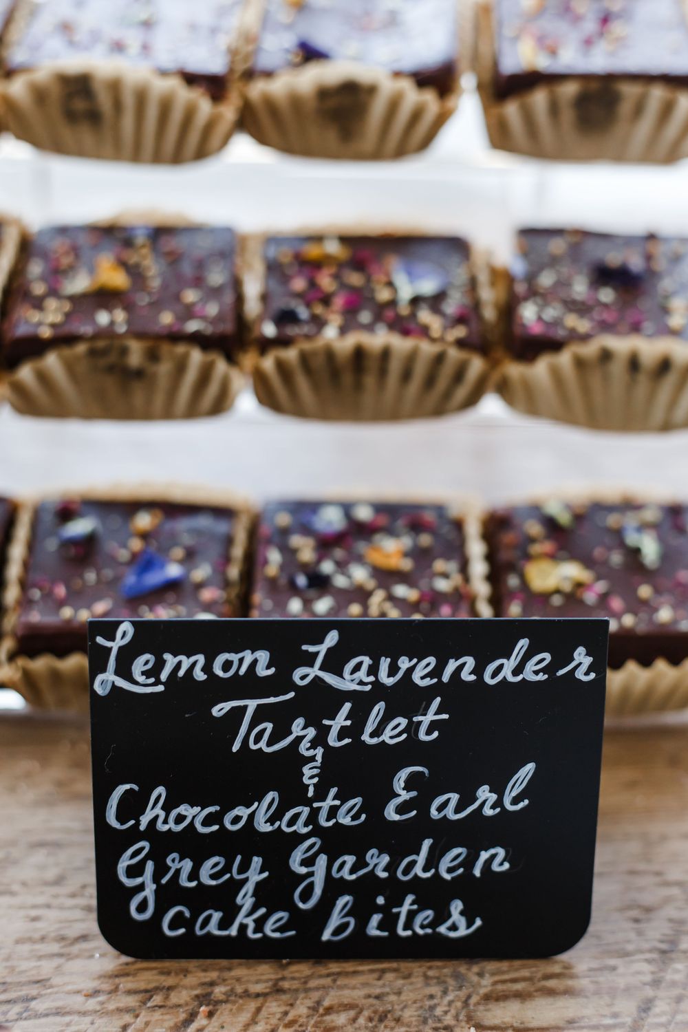 Chalkboard sign displaying menu items for Lemon Lavender Tartlet and Chocolate Earl Grey Garden cake bites.