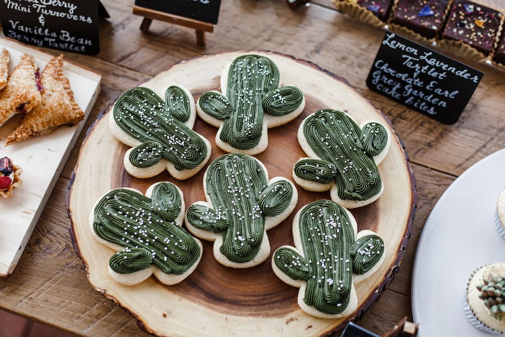 Decorative green shamrock cookies with white writing displayed on wooden boards.