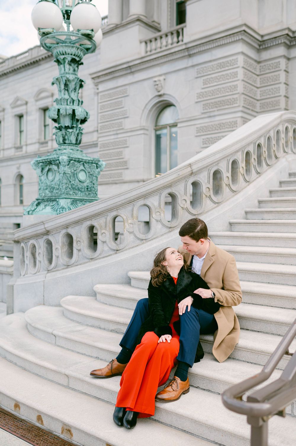 Couple sharing romantic moments on ornate marble steps of a grand building.