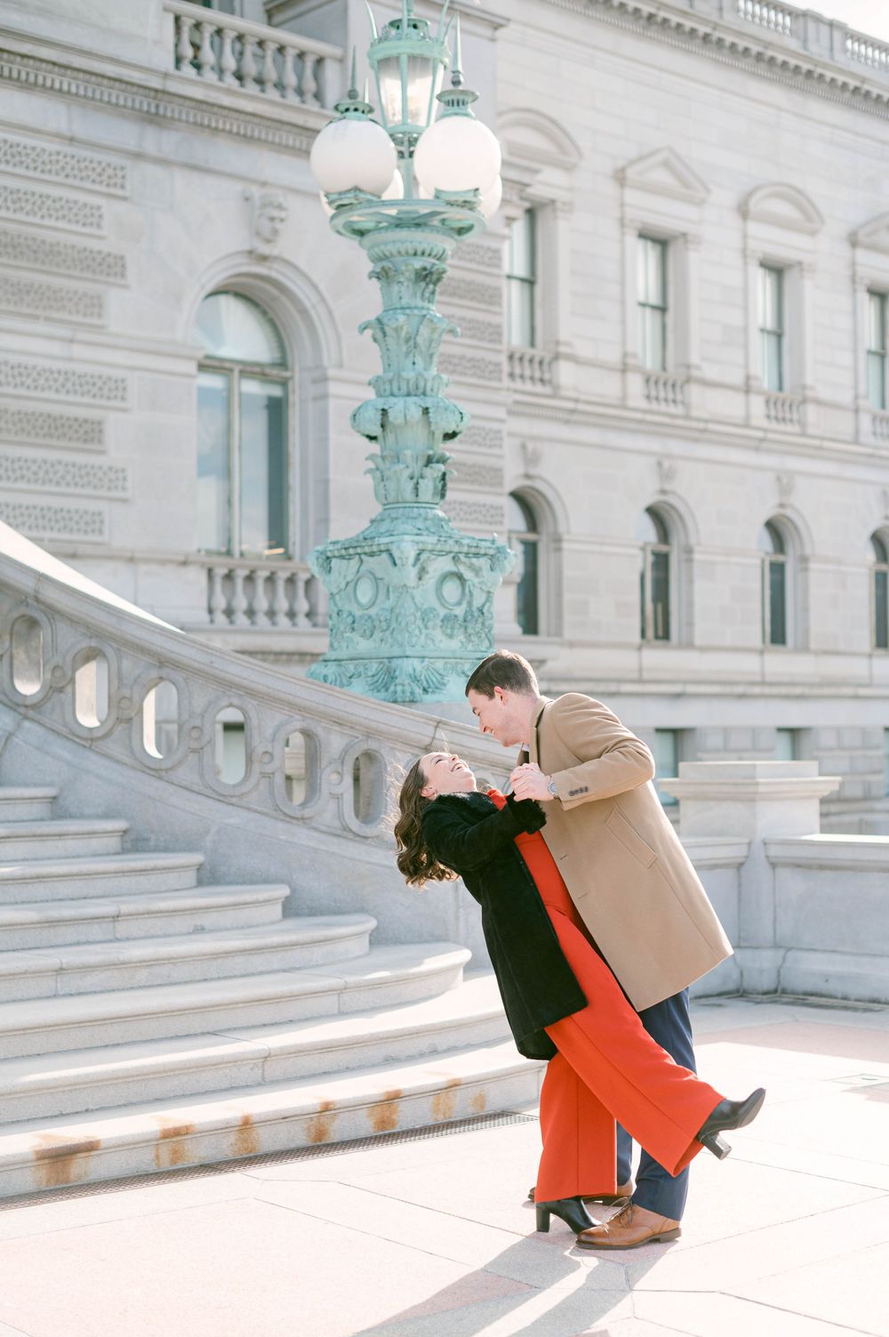 Joyful couple dancing and twirling on grand marble steps.