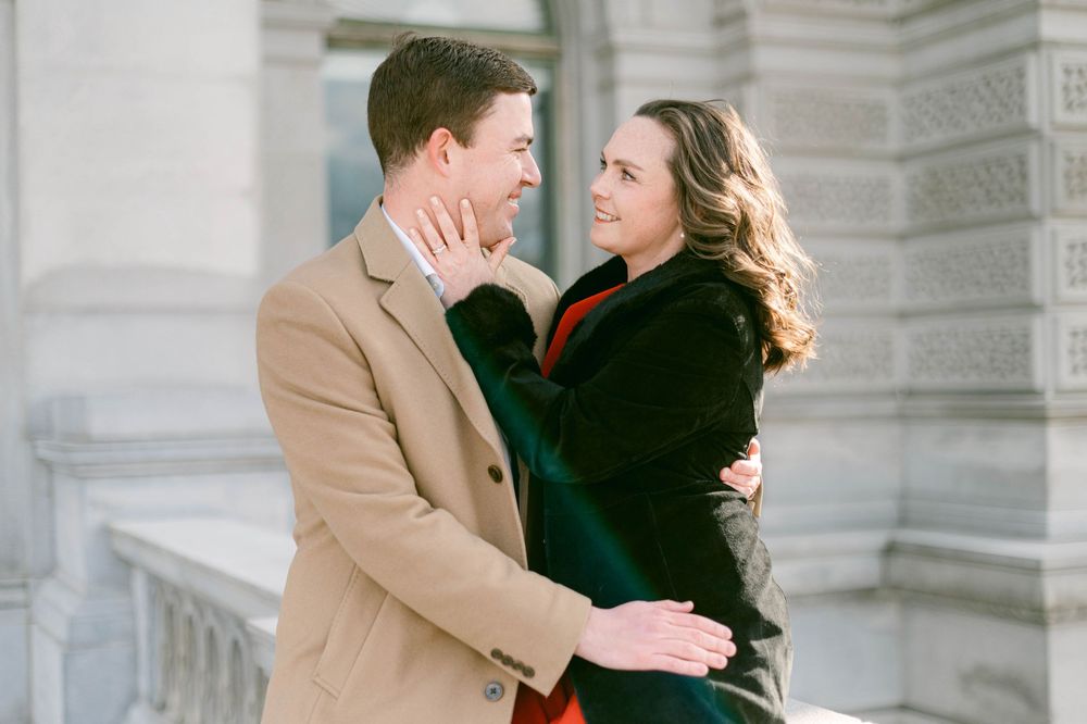 Intimate moment between couple against white stone architectural backdrop.