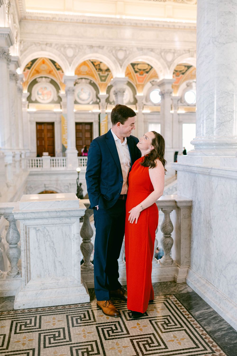 Couple posing in elegant marble hallway with geometric floor pattern.