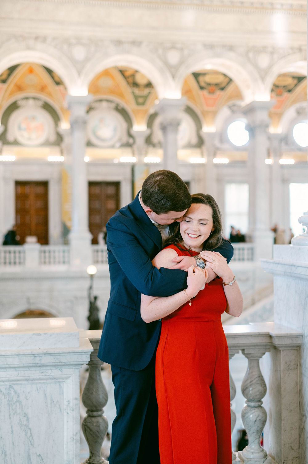 Candid moment of laughter in ornate marble corridor with arched ceilings.