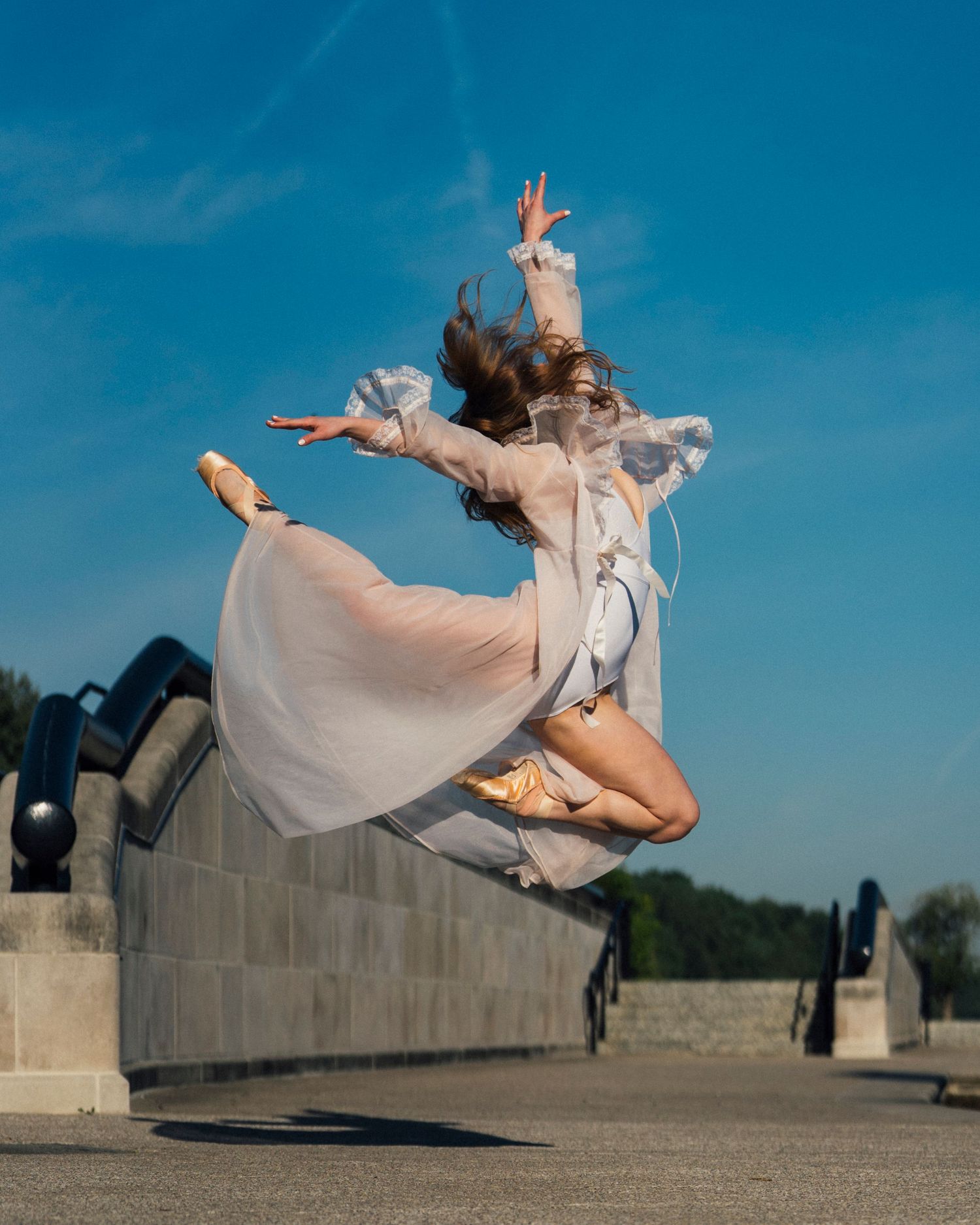 Ballet dancer leaping in the air near the water during a sunrise photoshoot at White River State Park in Indianapolis dance photography