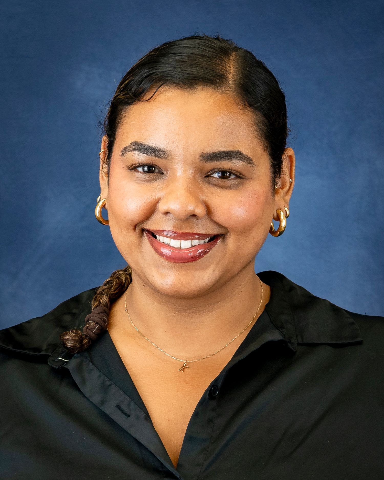 Studio portrait of a person in a black shirt against a blue background.