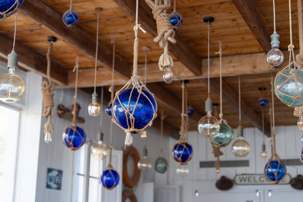 Cobalt blue glass ornaments and light fixtures hanging from wooden ceiling beams create an ethereal decorative display.