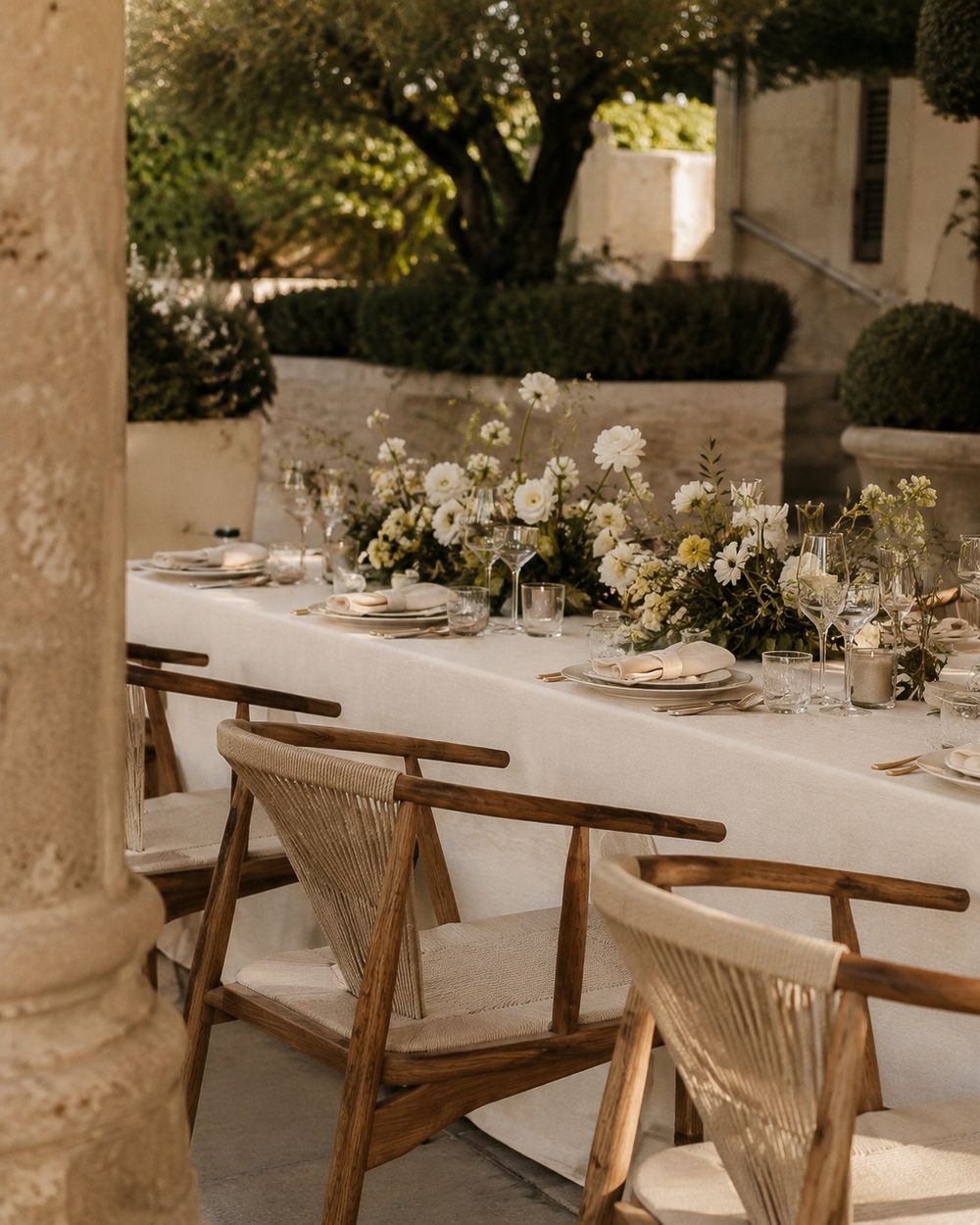 Outdoor wedding reception table with white linen and floral centerpieces in a stone courtyard in Valle de Guadalupe, Baja California.