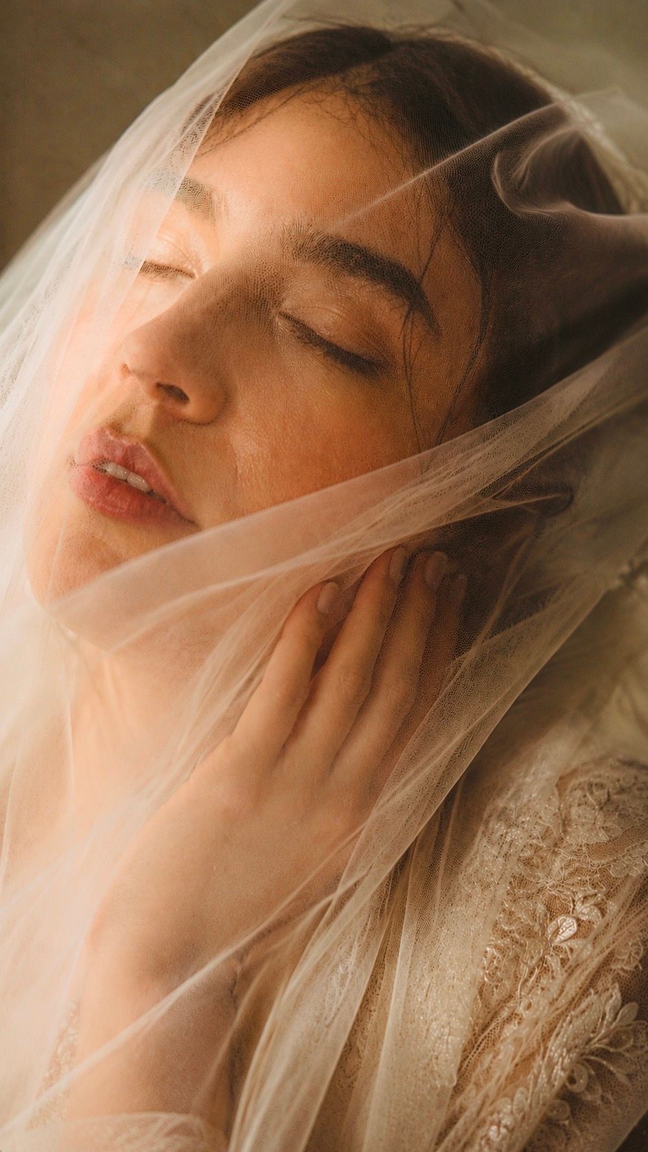 Serene bride with closed eyes beneath a soft tulle veil in warm light during her wedding in Valle de Guadalupe, Baja California.
