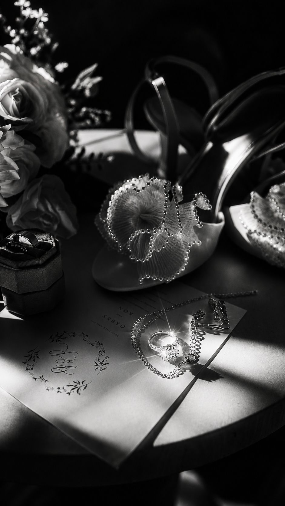 Black and white flat lay of wedding details, including heels, rings, and invitation in Valle de Guadalupe, Baja.