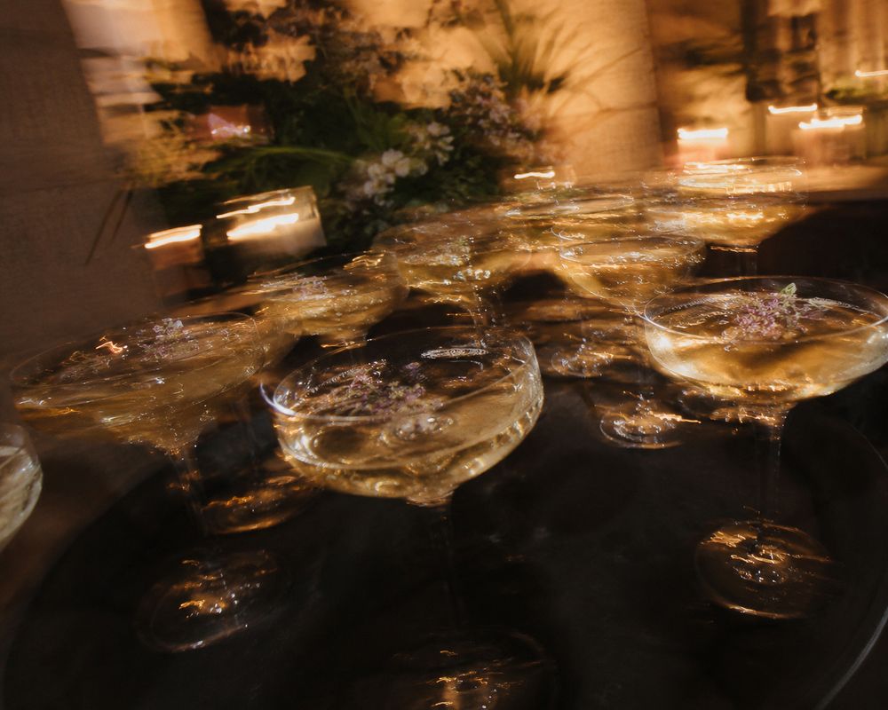 Motion-blurred champagne glasses on a tray at a dimly lit wedding reception in Valle de Guadalupe, Baja California.