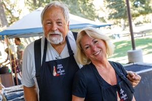 A group of festive volunteers enjoying themselves at an outdoor community event on a sunny day.