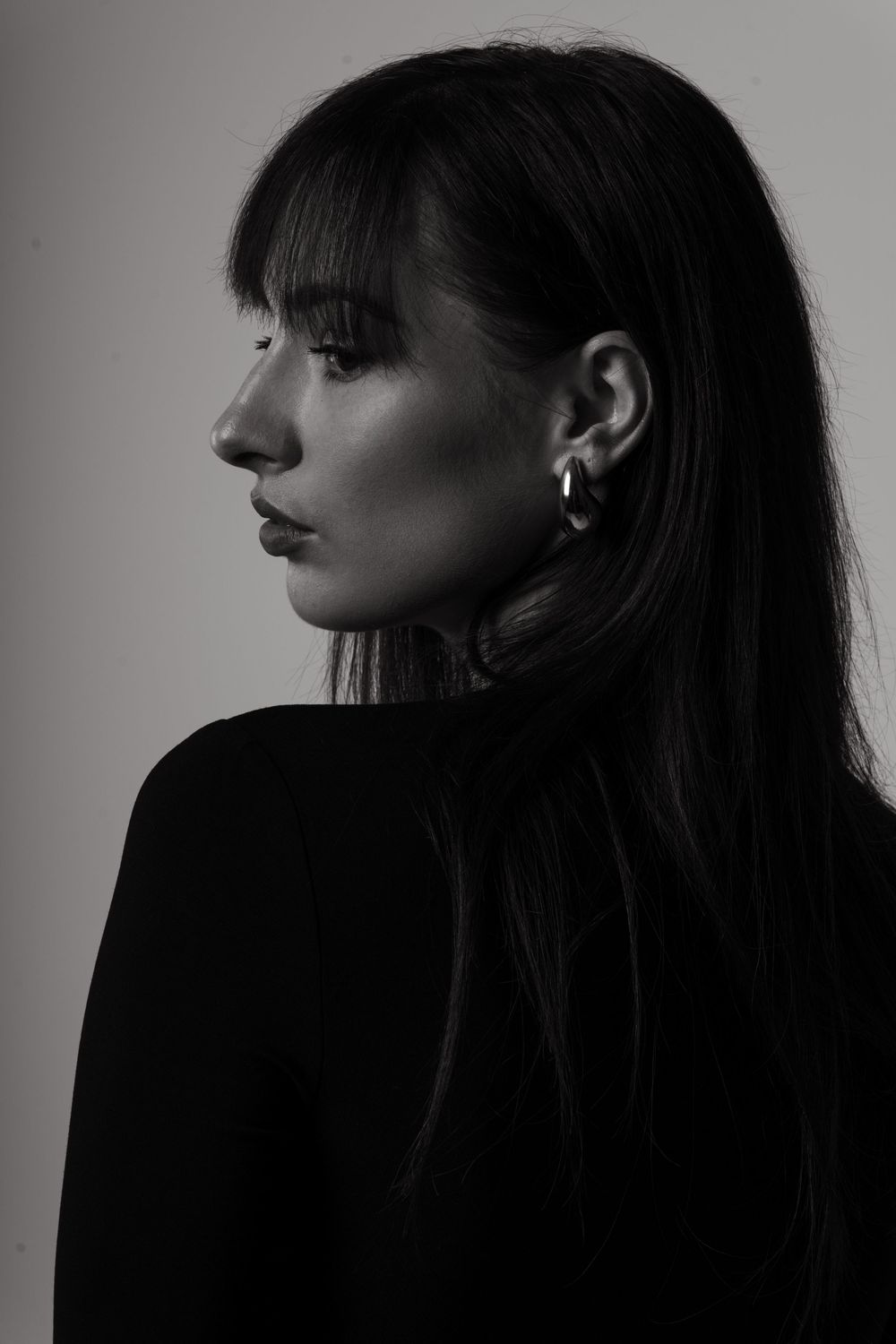 Kobieca elegancja — minimalistyczny portret w czarnej sukience, stylizowany w studio.