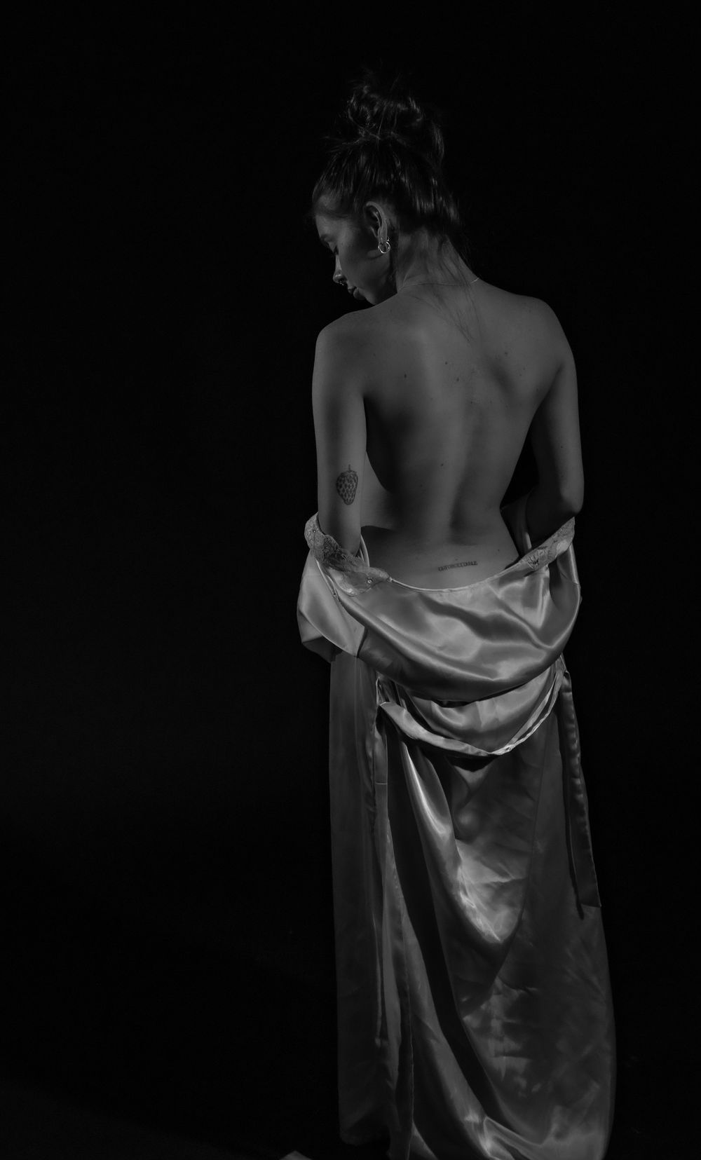 Artistic black and white photo showing bare back with draped satin fabric.