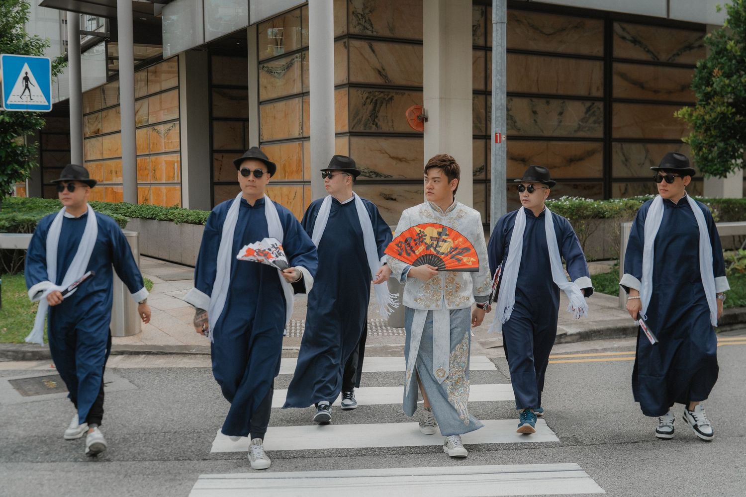 A group of people in navy blue suits walking together past a modern building exterior.