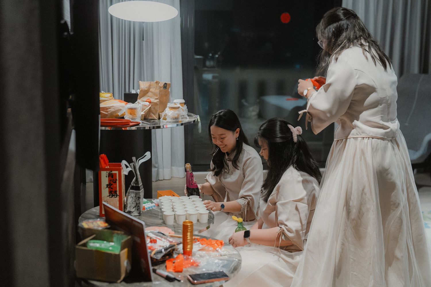 Wedding preparation scene with decorations and table settings in a dimly lit room.