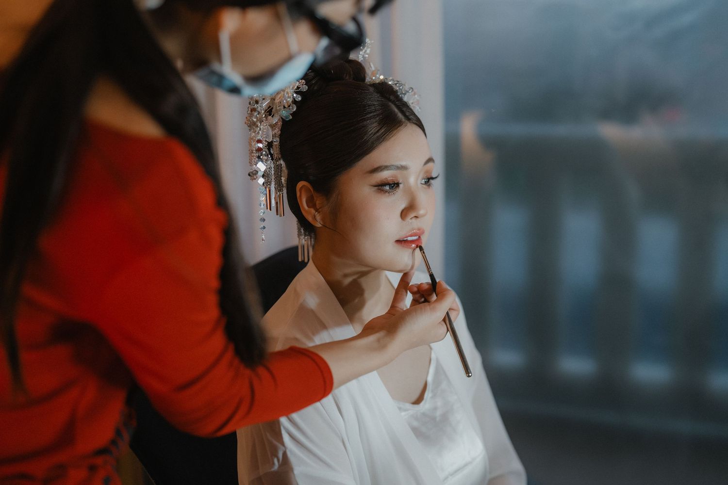 Preparation scene with makeup being applied in a softly lit setting.