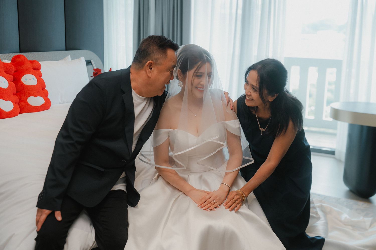 Candid wedding preparation moments show the bride getting ready with assistance from stylists in a bright hotel room.