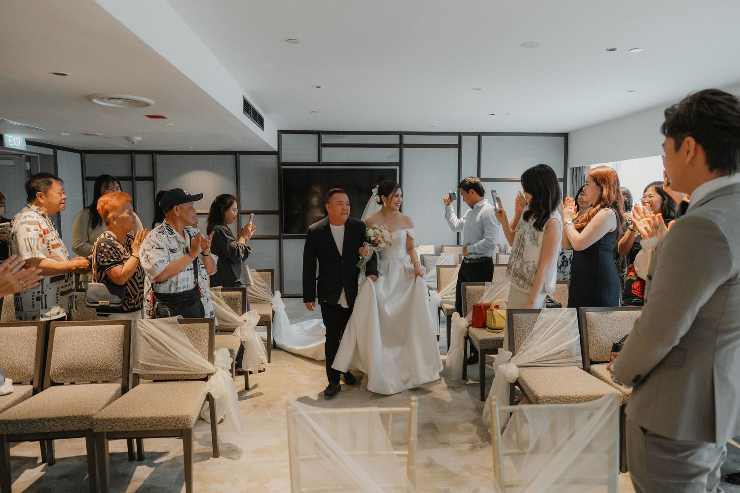 Group of wedding guests gather in a modern space watching and clapping during a reception celebration.