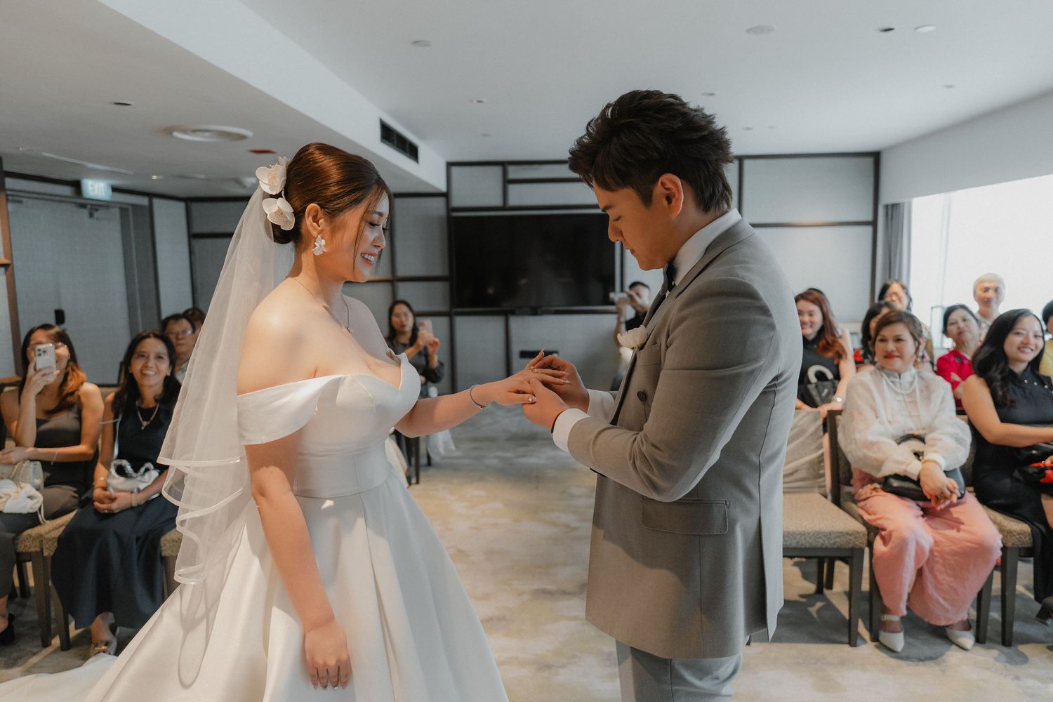 Wedding party members dance and celebrate together during a joyful reception in a bright indoor venue.