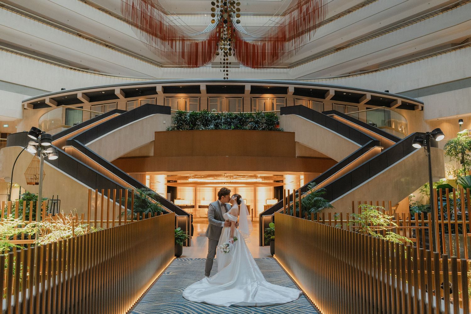 An elegant wedding venue with a dramatic staircase decorated with greenery and lighting for a ceremony.