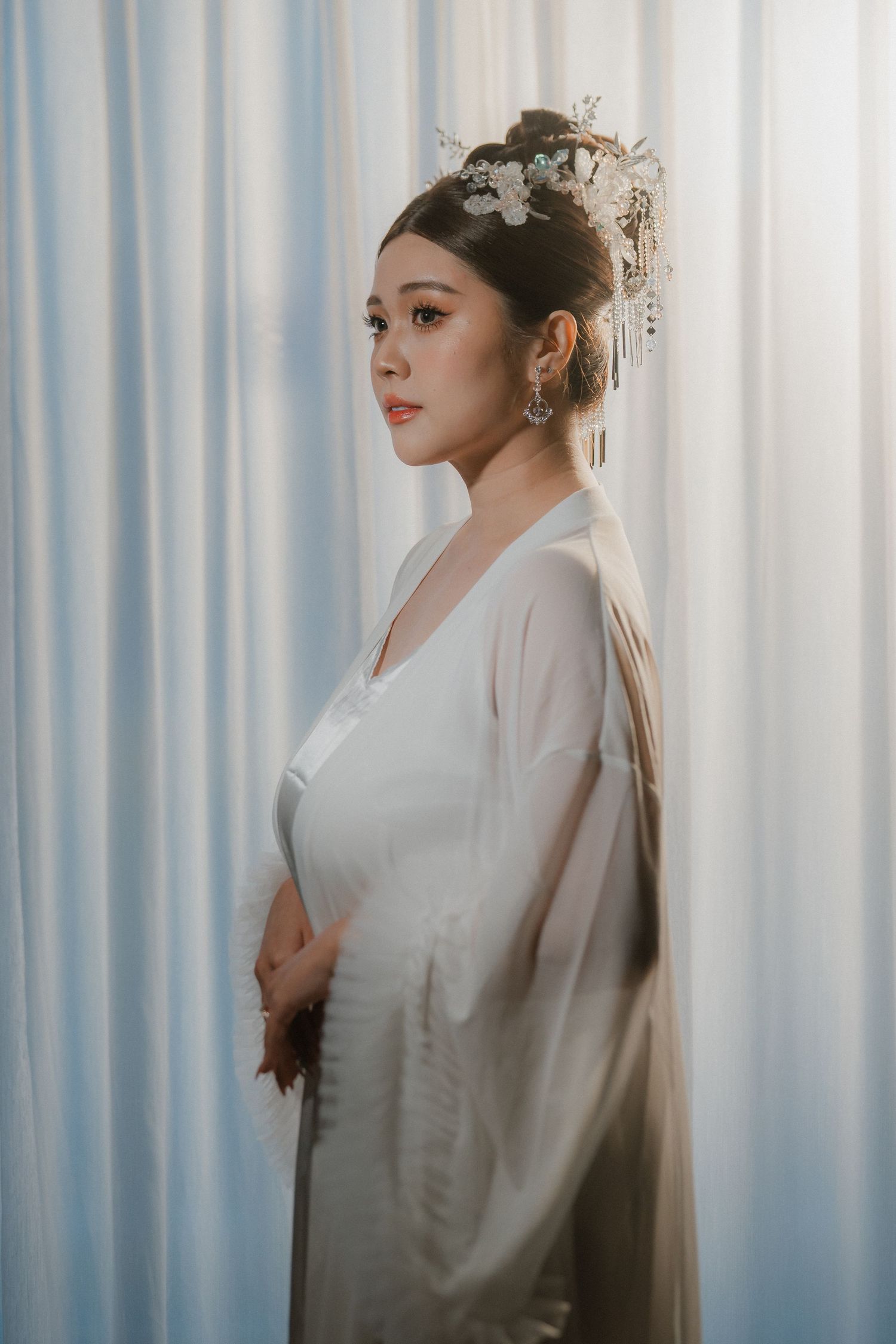 Elegant bridal portrait series with white curtains and traditional Chinese wedding attire.
