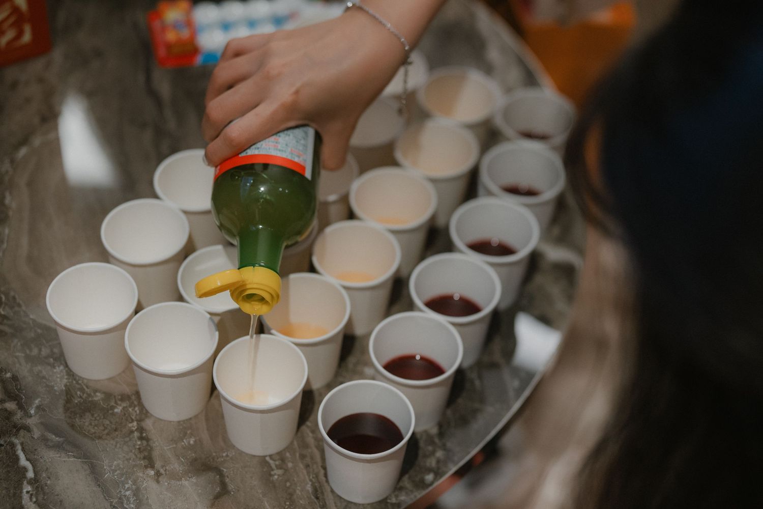 Various drinks being served in small white cups on a silver serving tray.