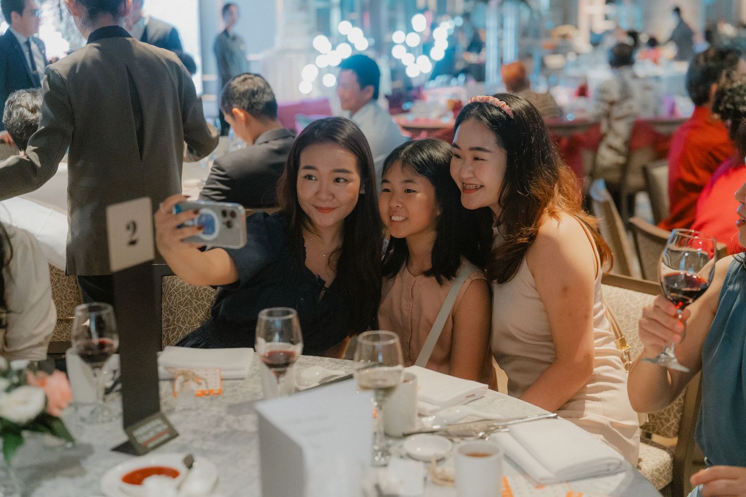 Wedding guests taking selfies and socializing at an elegant reception dinner table.