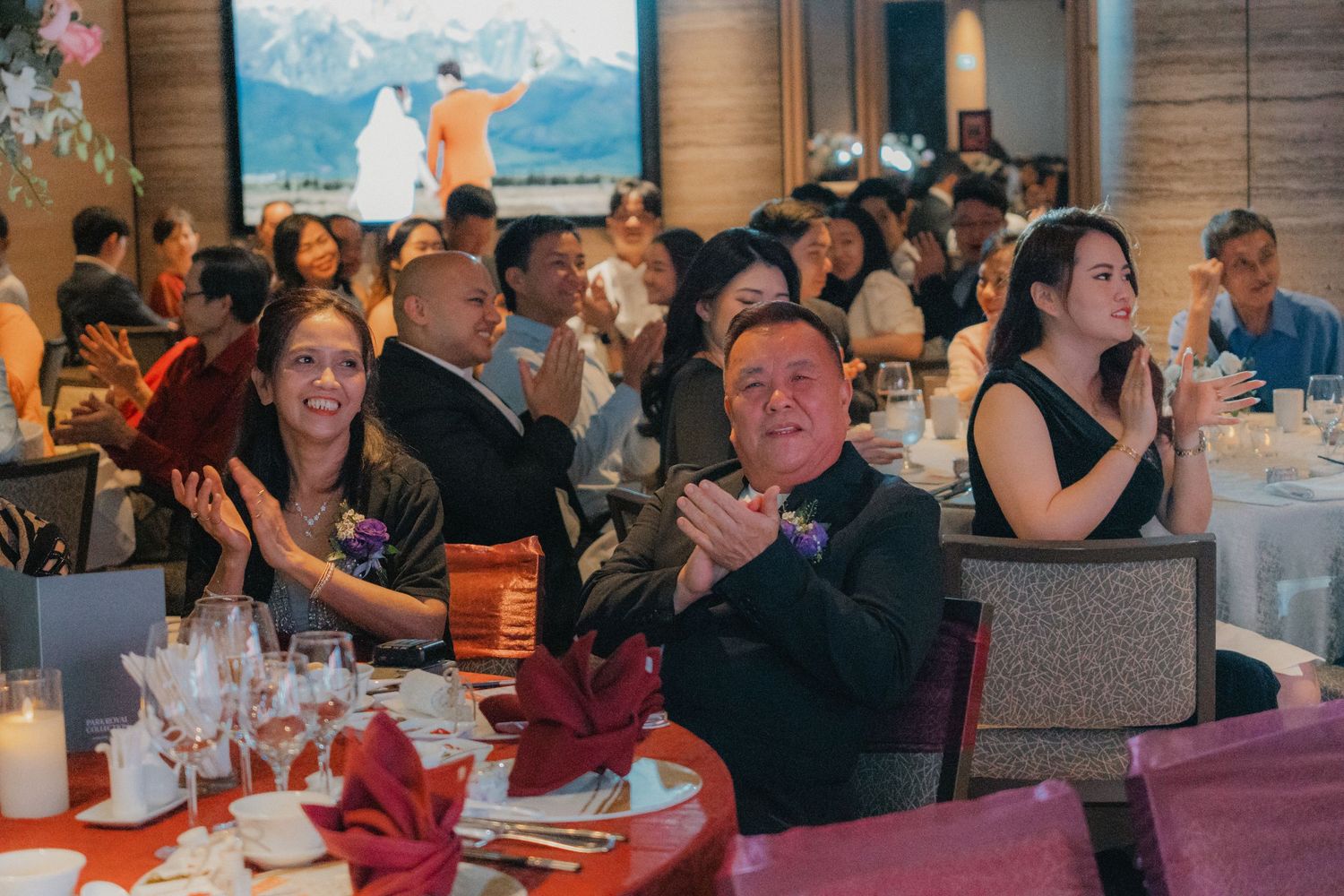 Wedding reception guests seated at decorated tables in a modern venue with ambient lighting.