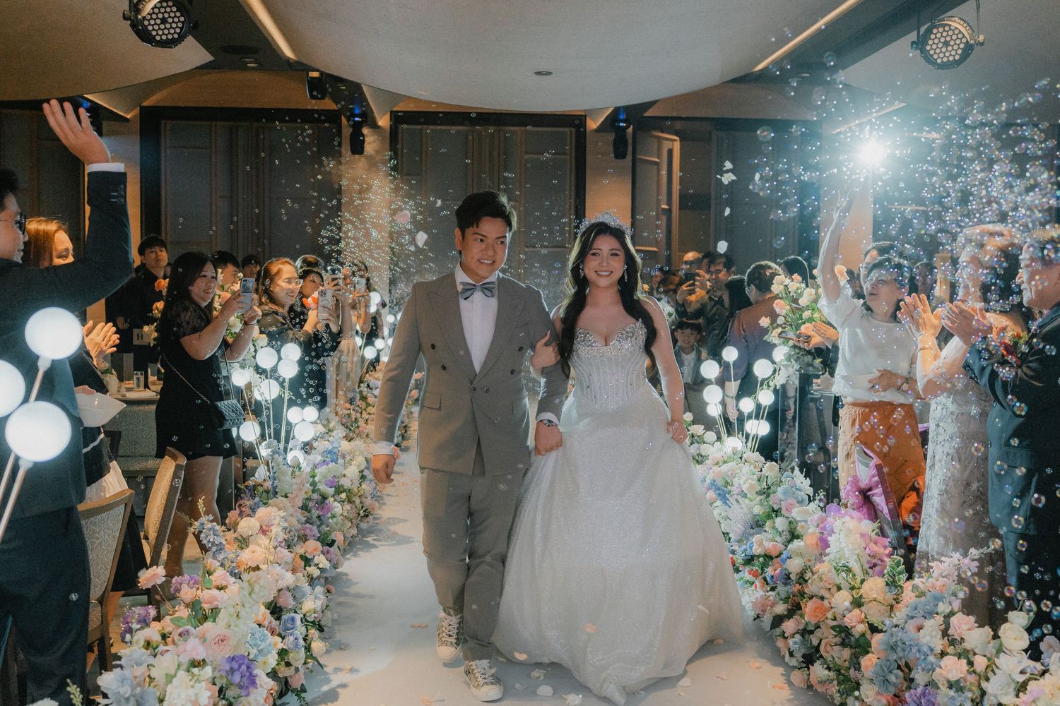 Wedding venue illuminated with white balloon decorations and floral arrangements along the aisle.