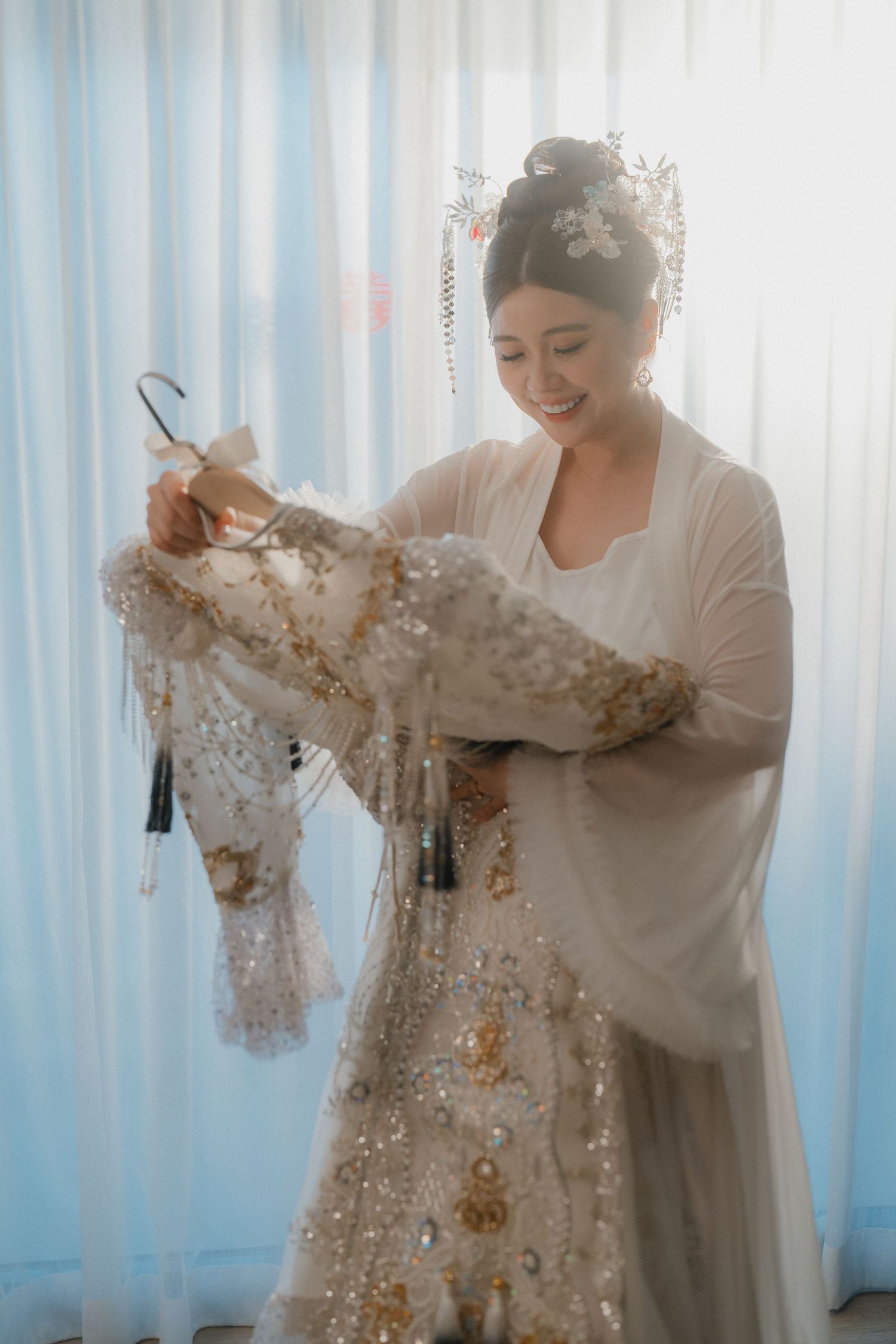 A detailed lace wedding dress being prepared in soft morning light.