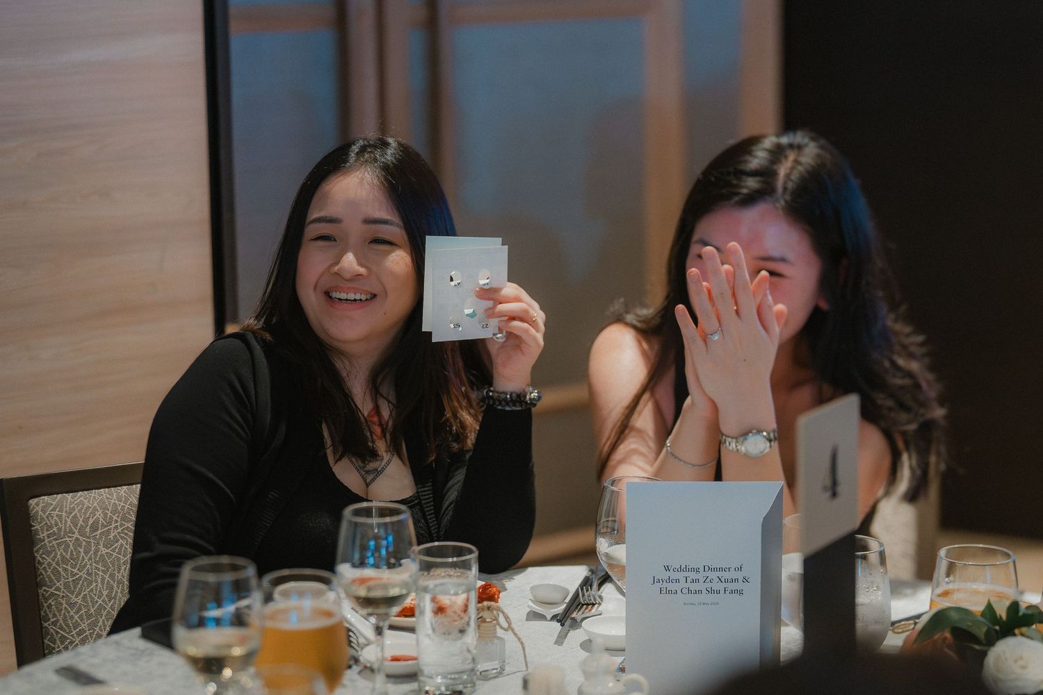 Two people share a candid moment while dining at a restaurant with drinks and cards on the table.