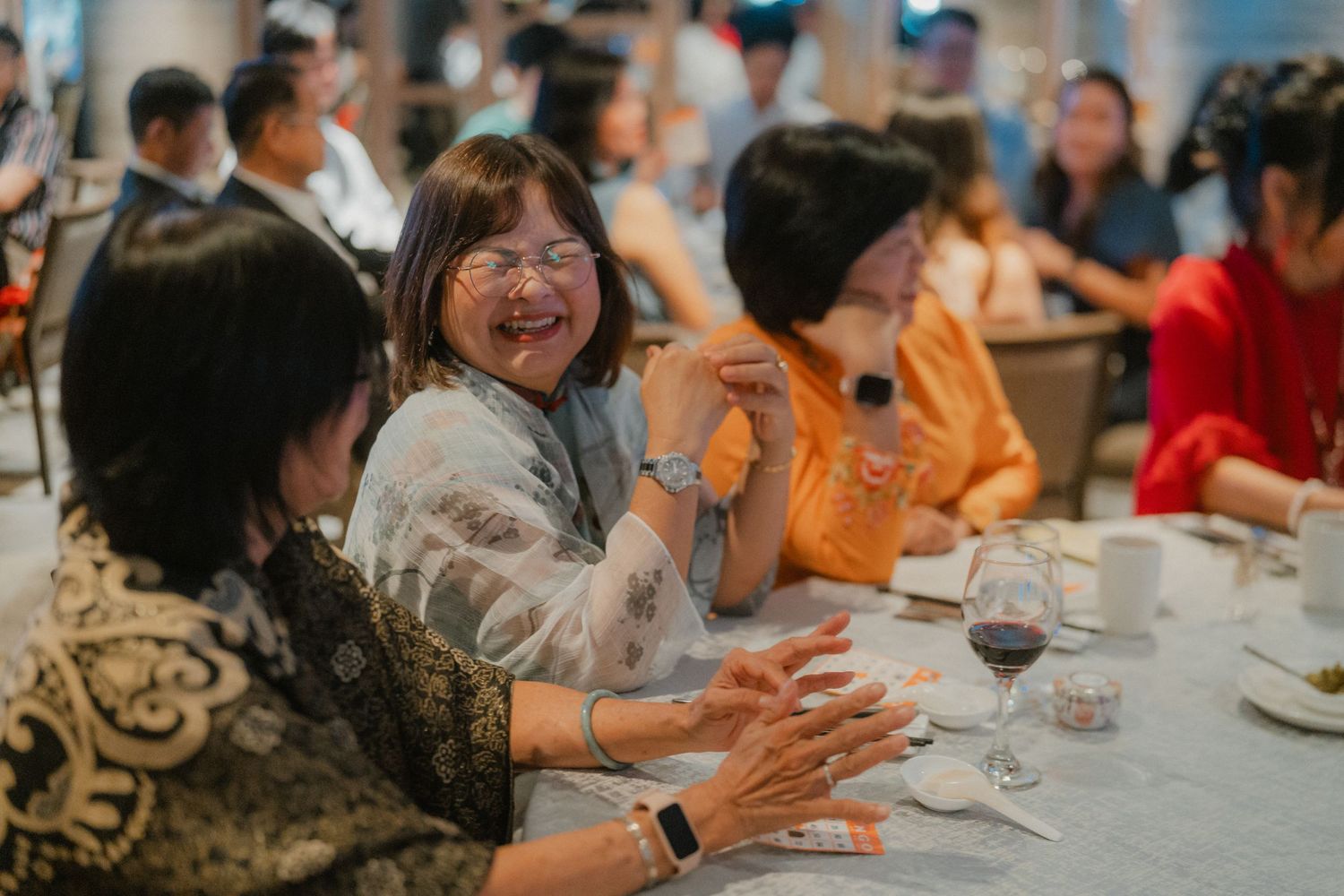 Wedding reception guests enjoying dinner at elegantly set round tables.