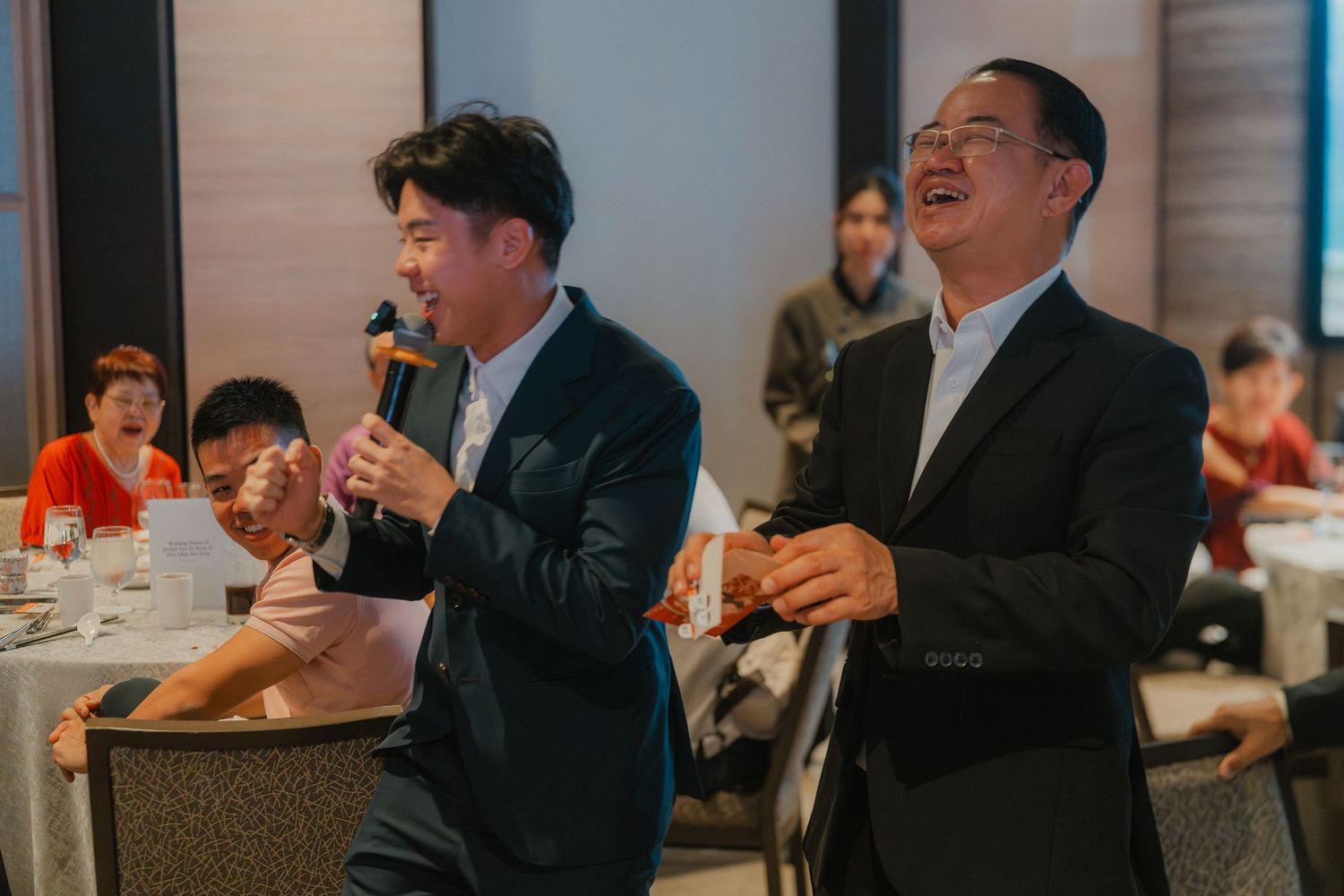 Two guests singing or speaking enthusiastically at wedding reception celebration.