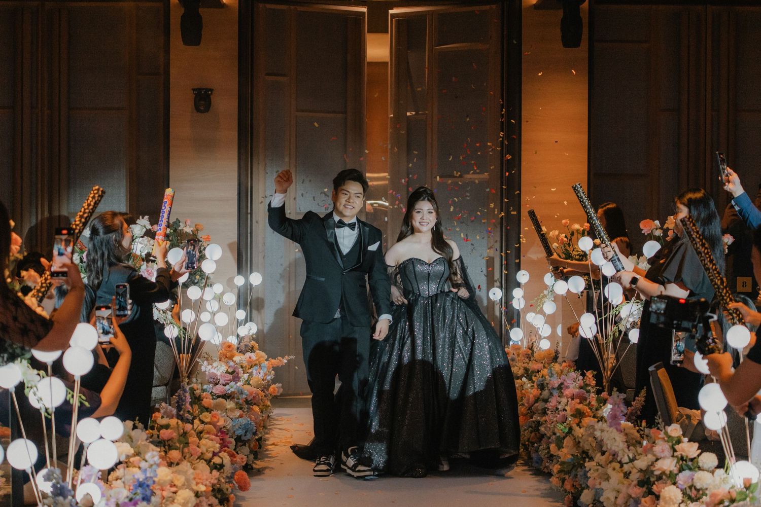 Wedding guests enjoying festivities in a venue decorated with glowing orbs and floral elements.