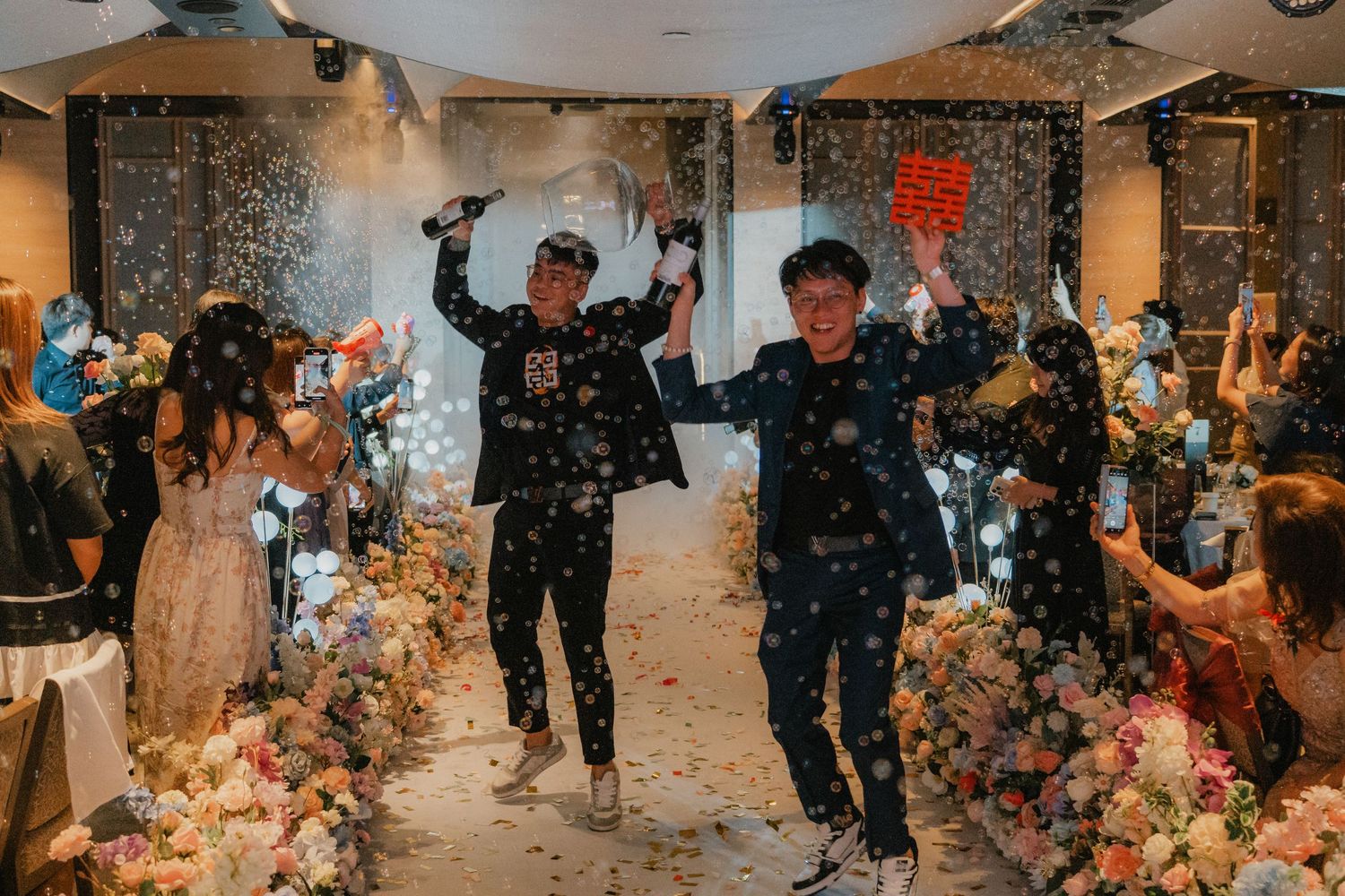 Joyous wedding celebration with guests throwing confetti in an indoor venue.