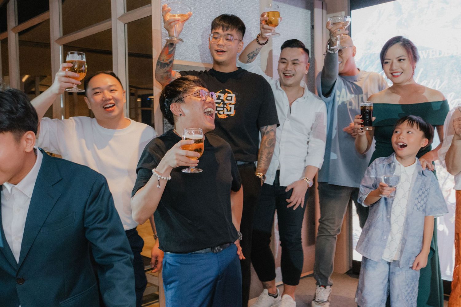 Wedding guests raising glasses and toasting during a celebration at an indoor reception venue.