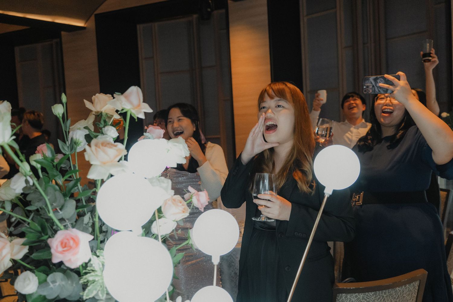 Reception guests dance and celebrate with illuminated LED balloon sticks at an evening wedding party.