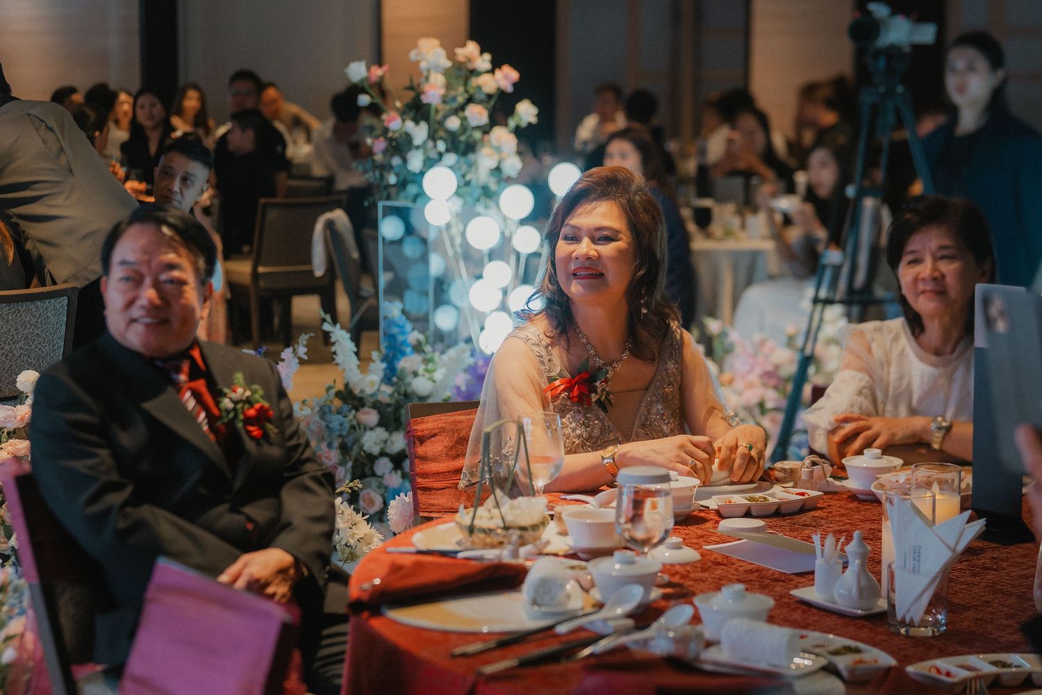 Guests seated at elegantly decorated tables with floral centerpieces during a formal dinner event.