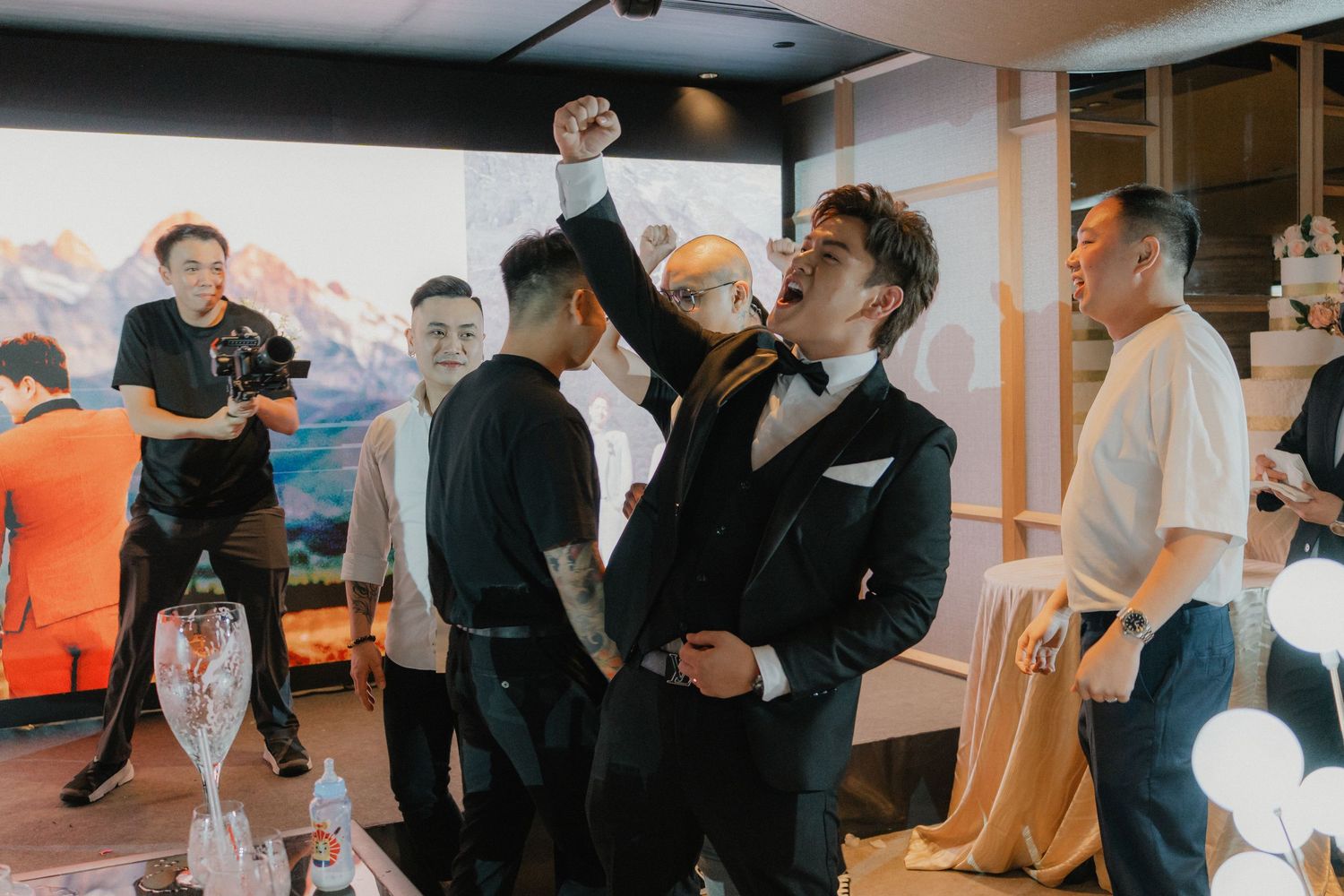 Wedding celebration with guests cheering and celebrating in a modern indoor venue.
