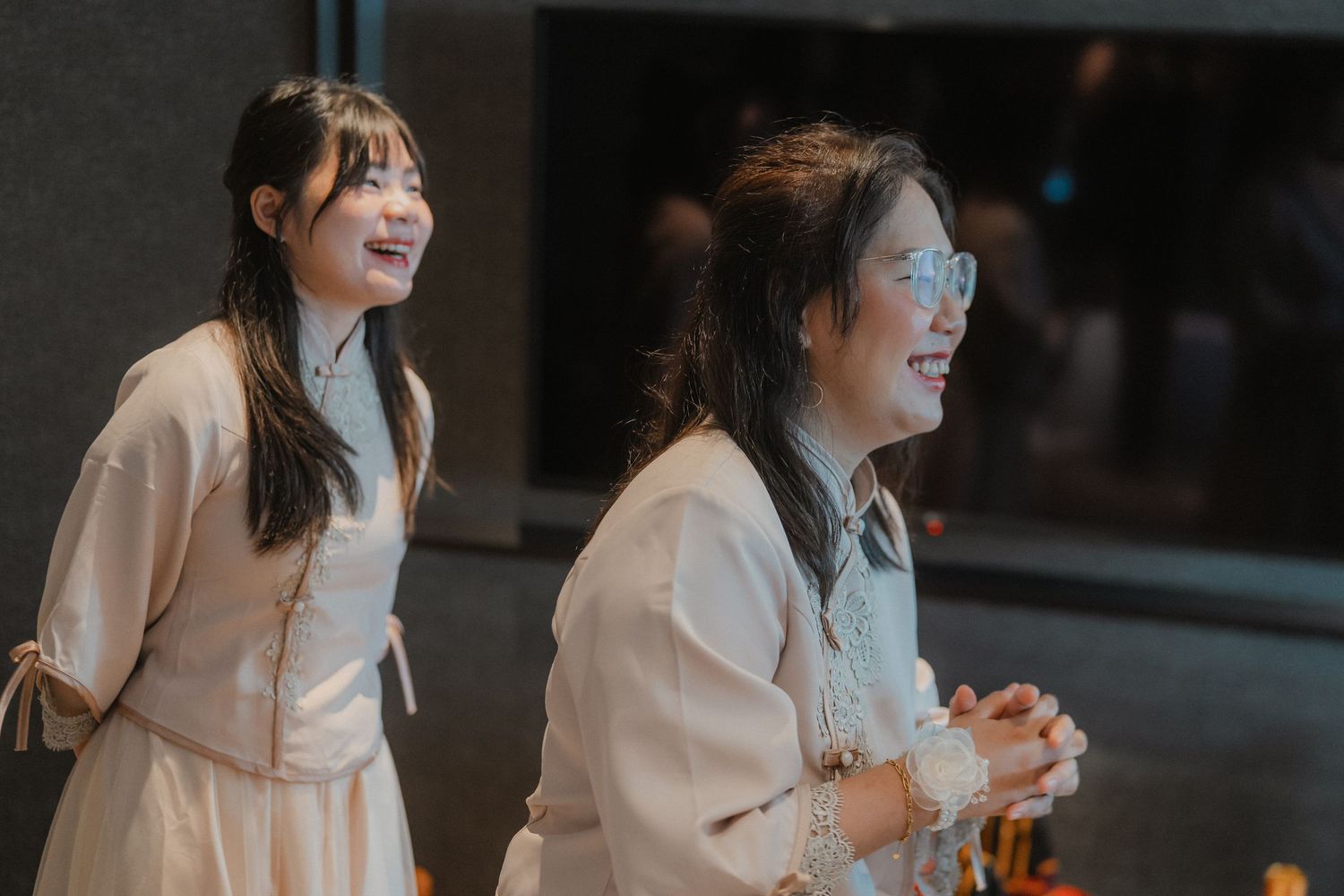 Wedding attendants in matching light-colored outfits share a joyful moment together.