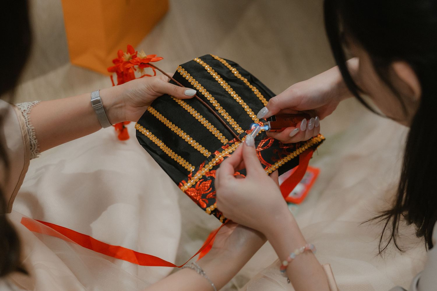 Hands exchanging traditional red envelopes decorated with gold stripes during a celebration.