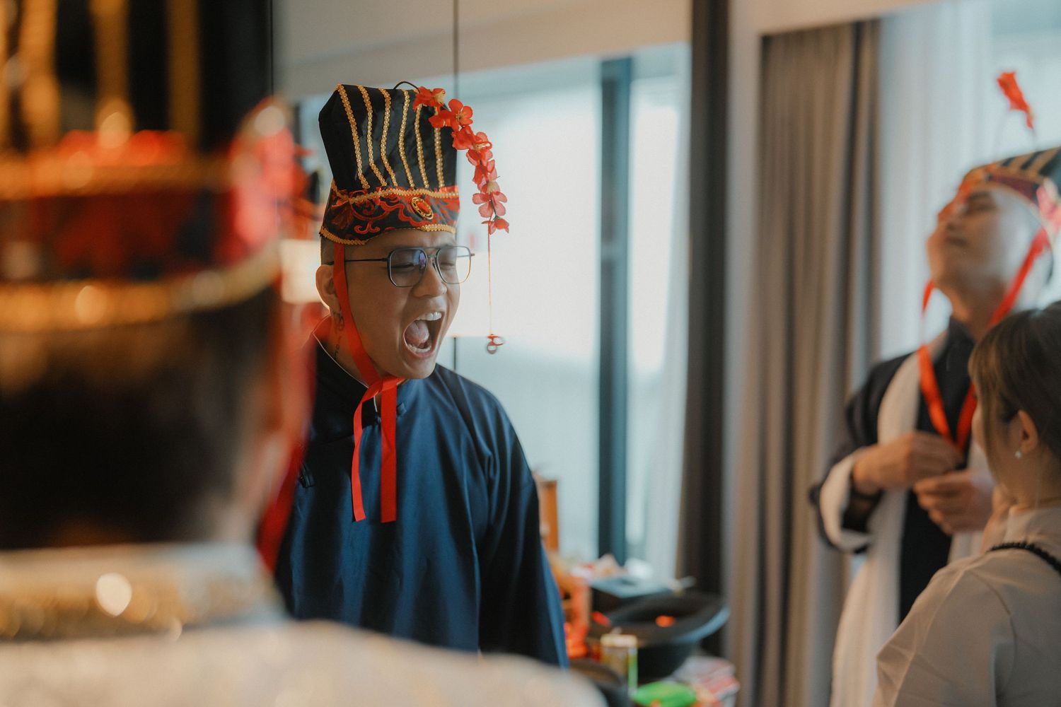 Person wearing traditional blue attire and decorative headgear at an indoor event.