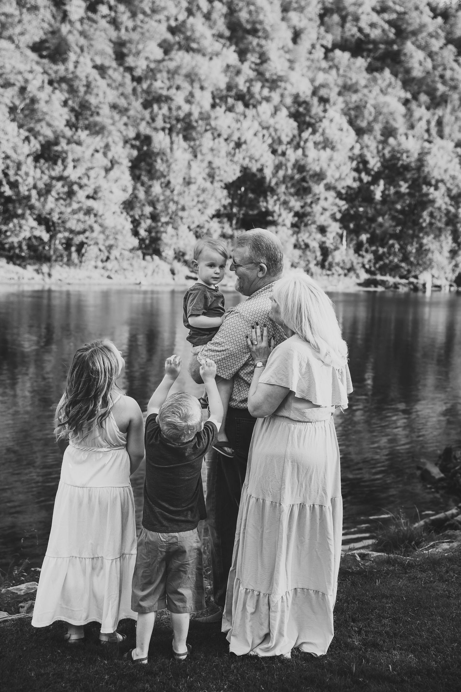 Family gathered by lakeside in black and white photo.