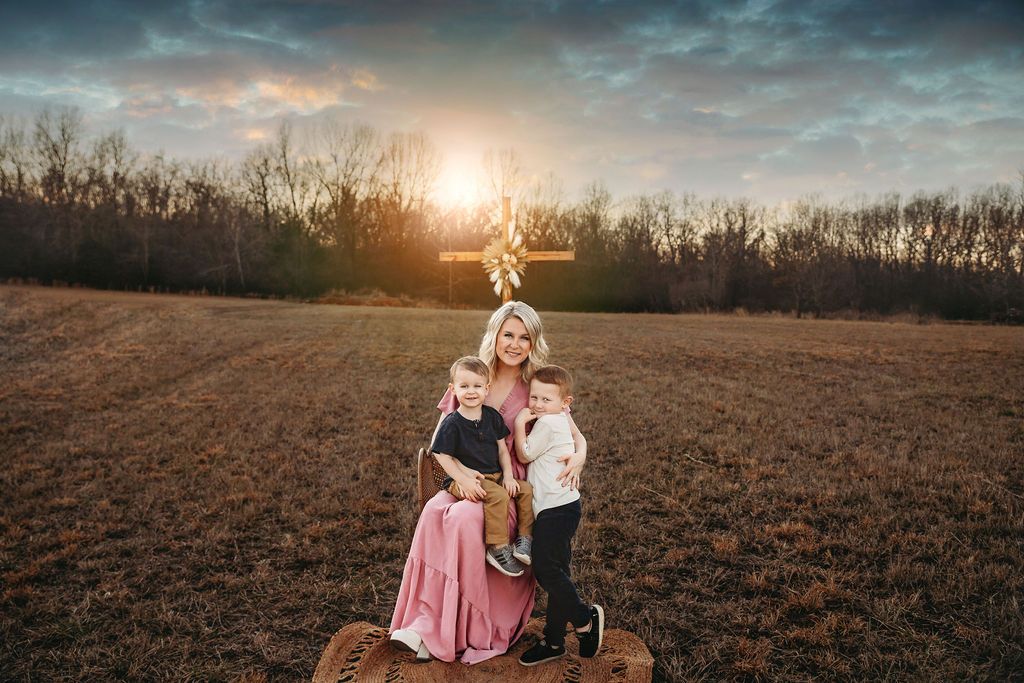 Romantic sunset photoshoot in an open field with soft golden lighting.