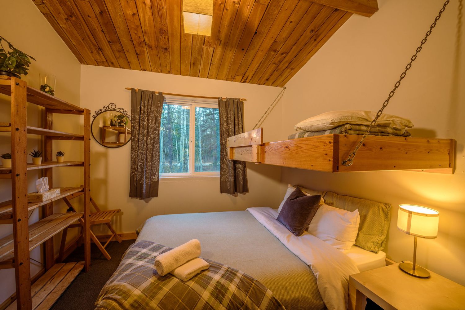 Cozy modern cabin interior with a wooden ceiling features multiple queen beds, bedside lamps, and rustic decor throughout.