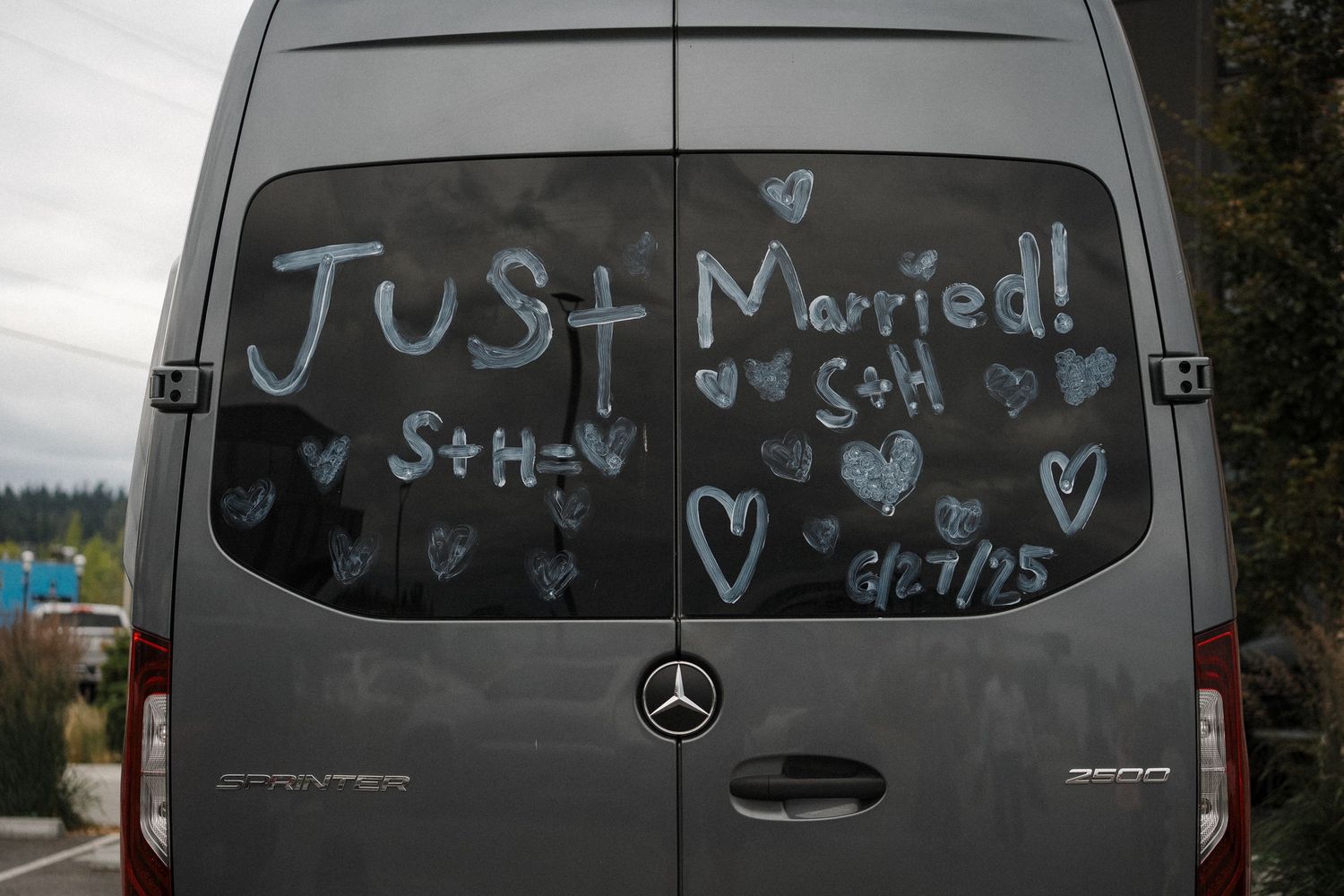 A silver Mercedes van with 'Just Married' and hearts drawn on the rear window in white writing.